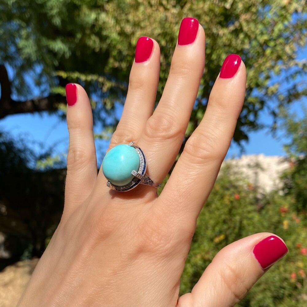 Check out this amazing ring with a center natural turquoise approx 6.5ct surrounded with natural sapphires that weigh approx. 2.60tcw and old European cut diamonds that
weigh approx. 0.43tcw. There is plenty of filigree and hand blading on the sides and under gallery of this amazing ring! Platinum Art Deco Turquoise Dome Ring with Sapphires & Diamonds