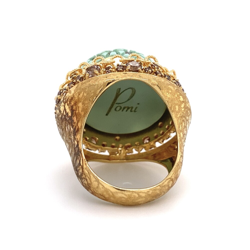 There are 76 natural pinkish brown round brilliant diamonds approx. 4.81tcw. The turquoise color center appears to be a resin and has the "Pomi" logo engraved on the inside bottom.
Pomi is a craft all-male , but very attentive to the needs of the woman universe .Pomi born as a jewelry with the intent to bring innovation in a strictly classic sector. An experienced team of designers study of current trends and create jewelry but with a unique flavor and sophistication. L'expertise master craftsmen apply in the original working strictly handmade in Italy . From the start , it was clear the need to create something that was recognizable and attributable only to Pomi. Pomi Designer Dome Ring with Resin and Diamonds 25.1g, s9