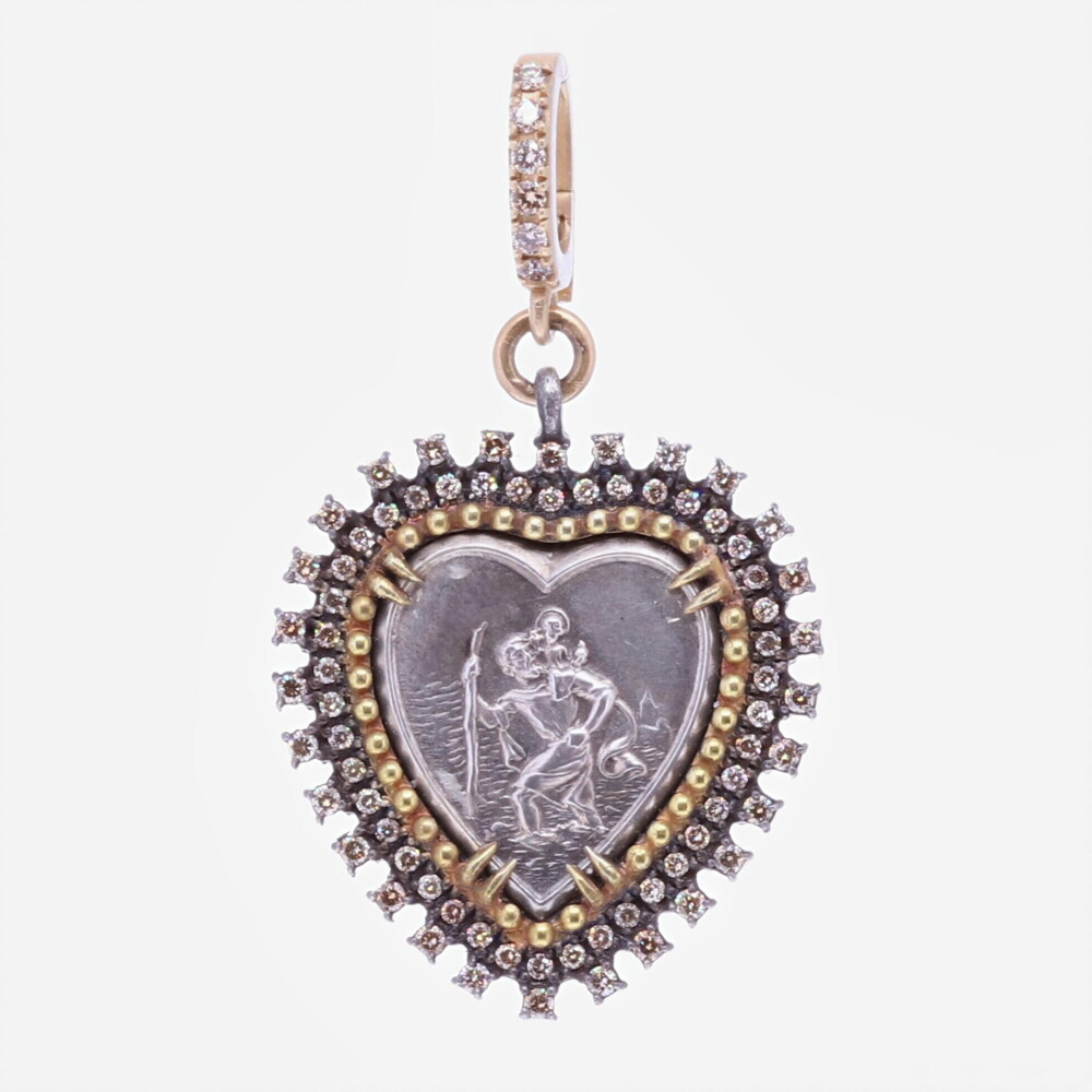 This beautiful antique medal represents St. Christopher and the iconic image "The Gentle Giant In The River". He was consulted by a wise old man that suggested he should use his strength to help people cross the dangerous river (where many lost their lives). Christopher thought providing this service would be pleasing to Christ. Christopher was eagerly preforming this task when a child asked for help to cross the river. As Christopher carried him on his shoulder, the child got heavier and heavier. When they got to the other side of the riverbank, Christopher asked the Child who he was. It turns out the child was Christ himself. This pendant is set in a unique diamond 0.59 tcw and gold 1.38g bezel. The bale has a 4mm opening. St.Christopher "The Gentle Giant In The River" Heart Pendant