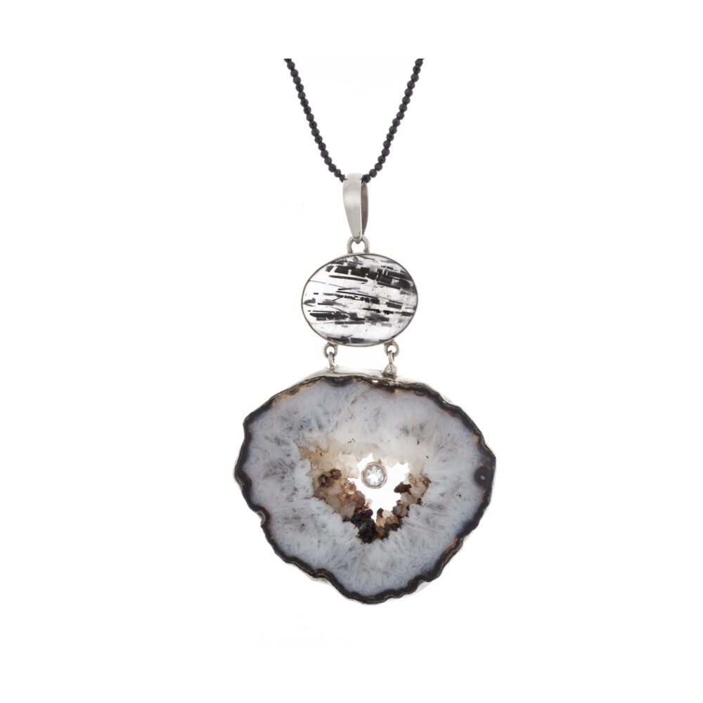 <font size="4"><span style="font-family: "EB Garamond";"><font size="4"><span style="font-family: "EB Garamond";">Large Black & White Agate Geode Pendant With Black Tourmalated Quartz Oval & Small Faceted White Topaz</span></font></span></font><div style="font-family: "EB Garamond";"><font size="4"><span style="font-family: "EB Garamond";"><font size="4">*Chains are sold separately </font></span><br style="font-family: "EB Garamond";"></font><div style="position: initial; margin: initial; font-family: "EB Garamond";"><br></div><div style="position: initial; margin: initial; font-family: "EB Garamond";"><p style="margin: initial; font-variant-numeric: normal; font-variant-east-asian: normal; font-stretch: normal; line-height: normal; font-family: "EB Garamond"; color: rgb(0, 0, 0); position: initial;"><font size="4"><font style="line-height: 22px; position: initial; margin: initial; font-family: "EB Garamond";">Formed from volcanic activity, a </font><span style="position: initial; margin: initial; font-family: "EB Garamond";"><font style="line-height: 22px; position: initial; margin: initial; font-family: "EB Garamond";">geode </font></span><span style="position: initial; margin: initial; font-family: "EB Garamond";">begins as a gas bubble rising</span></font></p><p style="margin: initial; font-variant-numeric: normal; font-variant-east-asian: normal; font-stretch: normal; line-height: normal; font-family: "EB Garamond"; color: rgb(0, 0, 0); position: initial;"><font style="line-height: 22px; position: initial; margin: initial; font-family: "EB Garamond";" size="4">within lava. Once the lava hardens, the bubble is a void, due to the</font></p><p style="margin: initial; font-variant-numeric: normal; font-variant-east-asian: normal; font-stretch: normal; line-height: normal; font-family: "EB Garamond"; color: rgb(0, 0, 0); position: initial;"><font style="line-height: 22px; position: initial; margin: initial; font-family: "EB Garamond";" size="4">earth's natural process of salt equalization where molten silica then</font></p><p style="margin: initial; font-variant-numeric: normal; font-variant-east-asian: normal; font-stretch: normal; line-height: normal; font-family: "EB Garamond"; color: rgb(0, 0, 0); position: initial;"><font style="line-height: 22px; position: initial; margin: initial; font-family: "EB Garamond";" size="4">methodically fills the gaseous voids. The various colors of geodes are</font></p><p style="margin: initial; font-variant-numeric: normal; font-variant-east-asian: normal; font-stretch: normal; line-height: normal; font-family: "EB Garamond"; color: rgb(0, 0, 0); position: initial;"><font style="line-height: 22px; position: initial; margin: initial; font-family: "EB Garamond";" size="4">determined by trace minerals present within each pocket. The cooling</font></p><p style="margin: initial; font-variant-numeric: normal; font-variant-east-asian: normal; font-stretch: normal; line-height: normal; font-family: "EB Garamond"; color: rgb(0, 0, 0); position: initial;"><font style="line-height: 22px; position: initial; margin: initial; font-family: "EB Garamond";" size="4">process will determine the size of crystals that form. The slower the</font></p><p style="margin: initial; font-variant-numeric: normal; font-variant-east-asian: normal; font-stretch: normal; line-height: normal; font-family: "EB Garamond"; color: rgb(0, 0, 0); position: initial;"><font style="line-height: 22px; position: initial; margin: initial; font-family: "EB Garamond";" size="4">temperature drops, the larger the crystals become. If the bubble fills</font></p><p style="margin: initial; font-variant-numeric: normal; font-variant-east-asian: normal; font-stretch: normal; line-height: normal; font-family: "EB Garamond"; color: rgb(0, 0, 0); position: initial;"><font style="line-height: 22px; position: initial; margin: initial; font-family: "EB Garamond";" size="4">fully, it is referred to as an agate.</font></p></div></div> Large Black & White Agate Geode Pendant With Black Tourmalated Quartz Oval & Small Faceted White Topaz