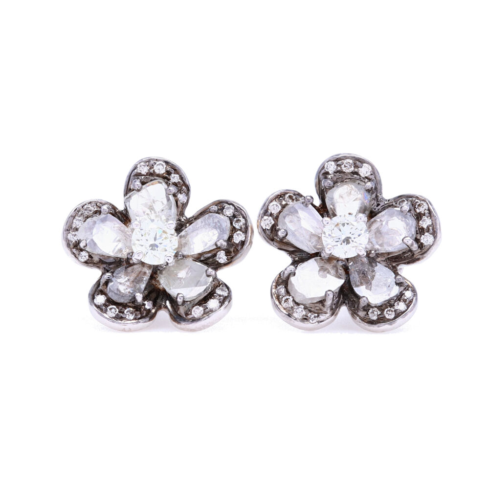 Black rhodium detail gives these flower diamond slice studs an edgy look while still maintaining a classic style. The pedals are surrounded by brilliant cut diamonds for a halo feel. These studs pair perfect with jeans and a t-shirt. !8k White Gold with Black Rhodium Diamond Slice Studs with White Diamond Halos