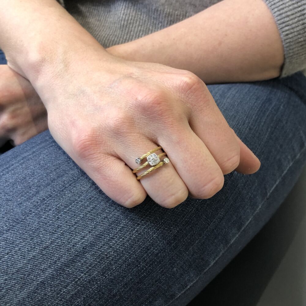 This unique heat treated yellow colored steel cable ring features a single square diamond setting in the center of the band, as well as two small circle settings of diamonds at the ends of the wrapped cable. With a total carat weight of .12cts, this ring has enough flirty and fun style to be worn during the day and then into your nightlife. Yellow Cable Flex Ring with Square Diamond Stations set in 18kt White Gold