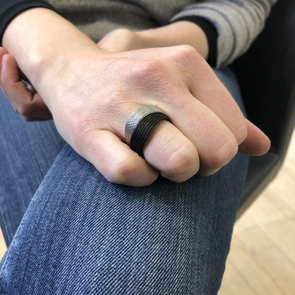 This heat treated black and grey colored steel cable features 6 rows of each color, with an 18k yellow gold accent. Two Tone Ring