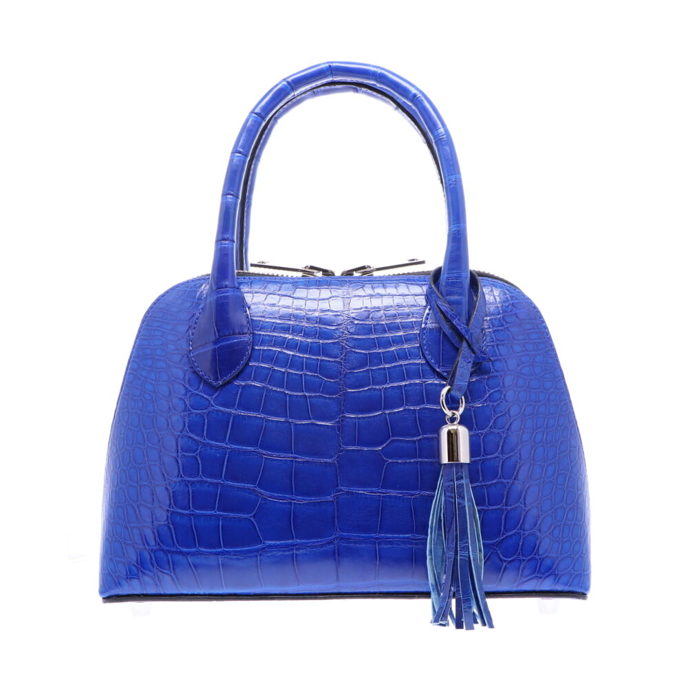 LaNae’s Small Dome is a top handle bag made of genuine American Alligator Skin. Proudly handcrafted in the USA by 3rd generation artisans, all edges are hand painted, interior is garment suede and is detailed with Italian palladium hardware. This classic style comes with a fun tassel that can be detached. The interior has a zippered and a cell phone pocket. Under the handles are D rings to attach the over the shoulder strap (up to 25”). Each luxury bag is one of a kind and especially made for you to stand out against the crowd!
Electric Blue Alligator in Small Dome