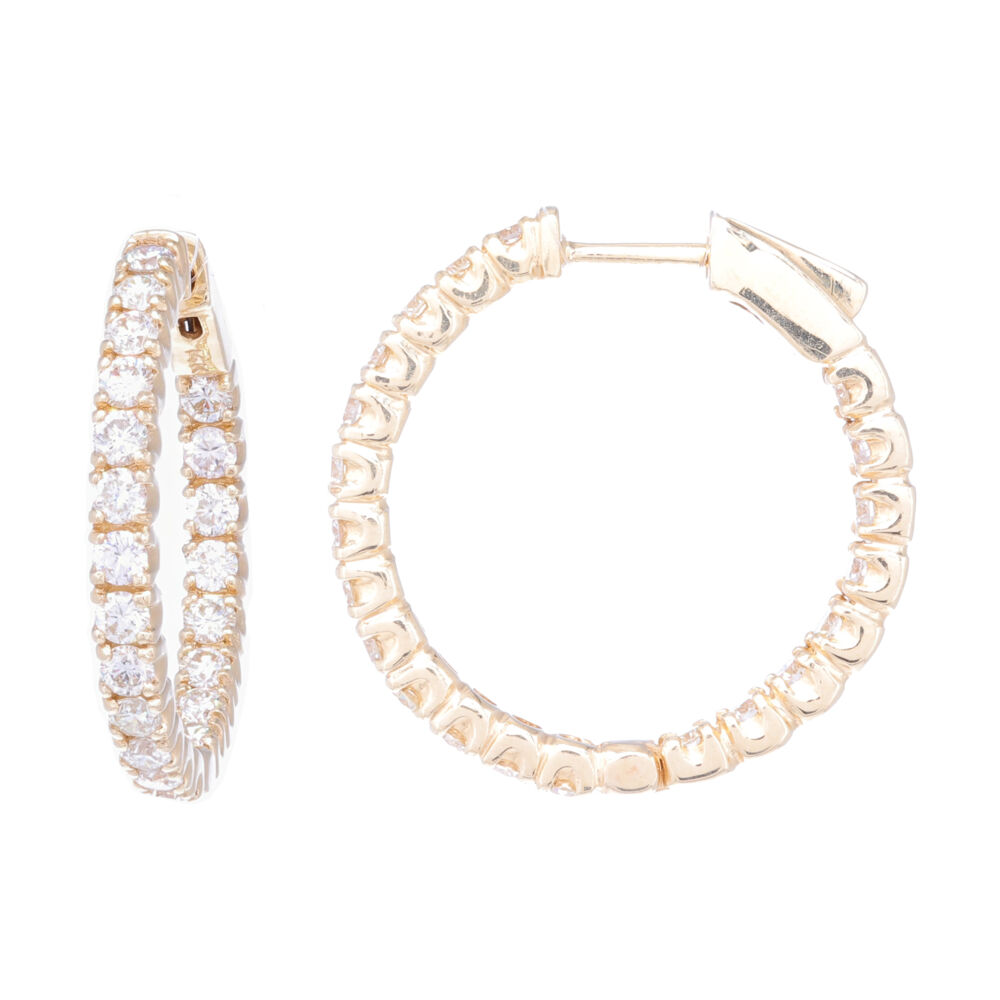 These round hoop earrings are featured in 18k yellow gold. Displaying larger pronged set diamonds down the front of the hoop, as well as on the inside on the back. Giving the illusion that there is an eternity circle of diamonds. Round Diamond In and Out Huggie Earring
