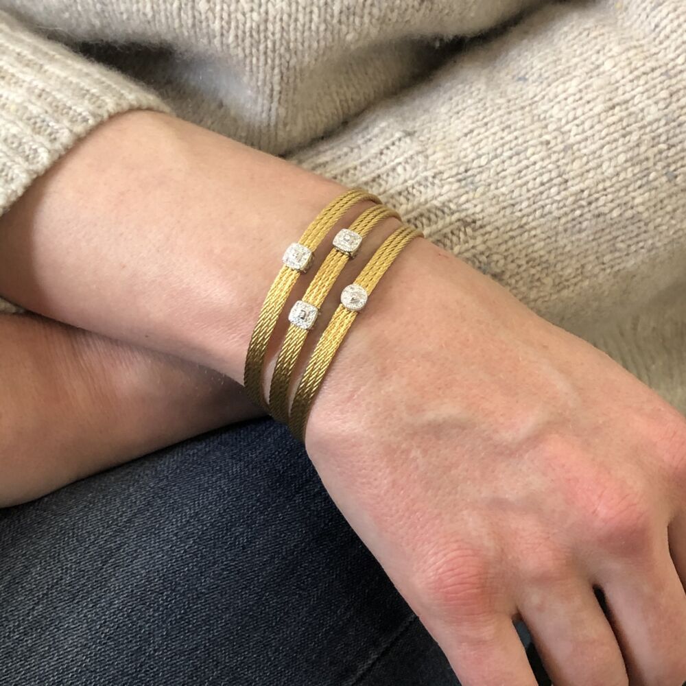 This heat treated yellow colored steel cable bangle features two 18k white gold diamond barrel stations. With a total diamond weight of .13 carats, this bangle is perfect to be stacked with others or to just wear alone. Yellow Two Station Bangle