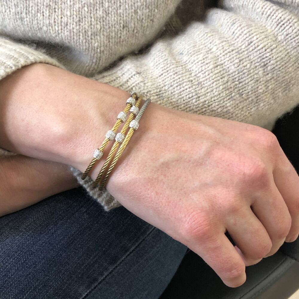 This heat treated yellow steel cable features five 18k white gold diamond barrel stations, with a total diamond weight of .34 carats. This bangle is perfect to stack with others or to wear alone. Yellow Five Station Bangle